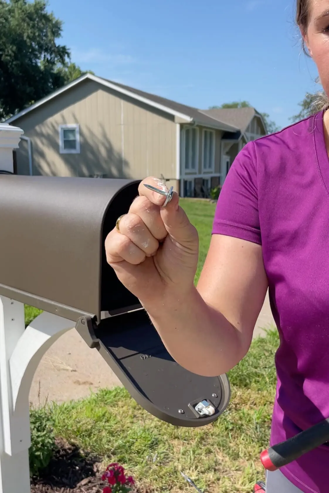 Using roofing nails to attach a mailbox to a wood corbel.